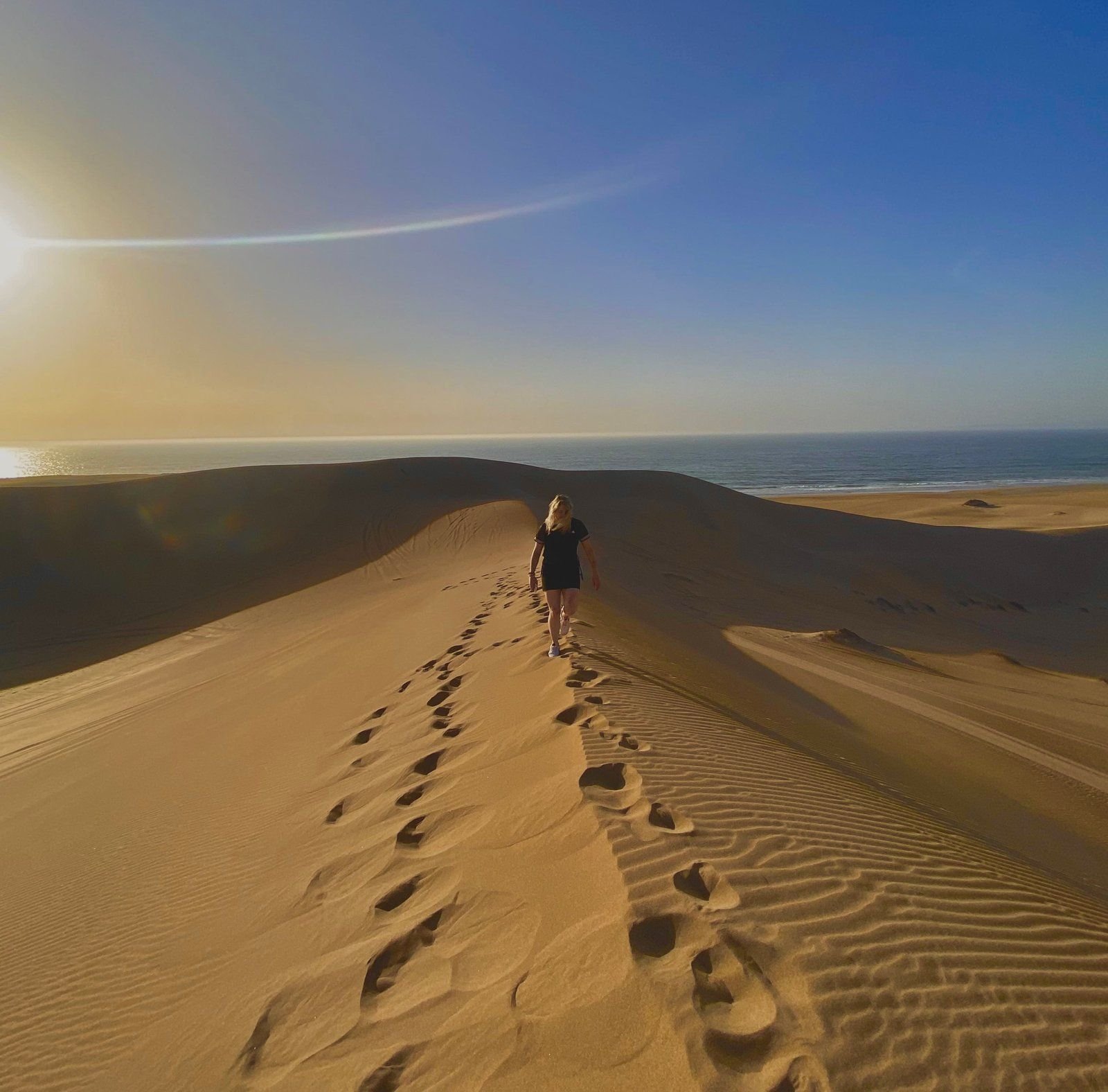 Surfer walking along a desert dune ridge near Agadir