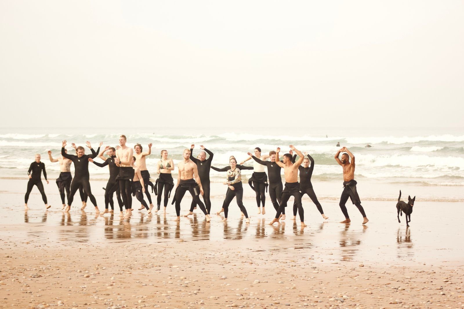 Surf group jumping for joy on the beach