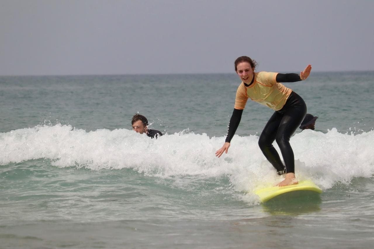 Student riding white water on a yellow surfboard