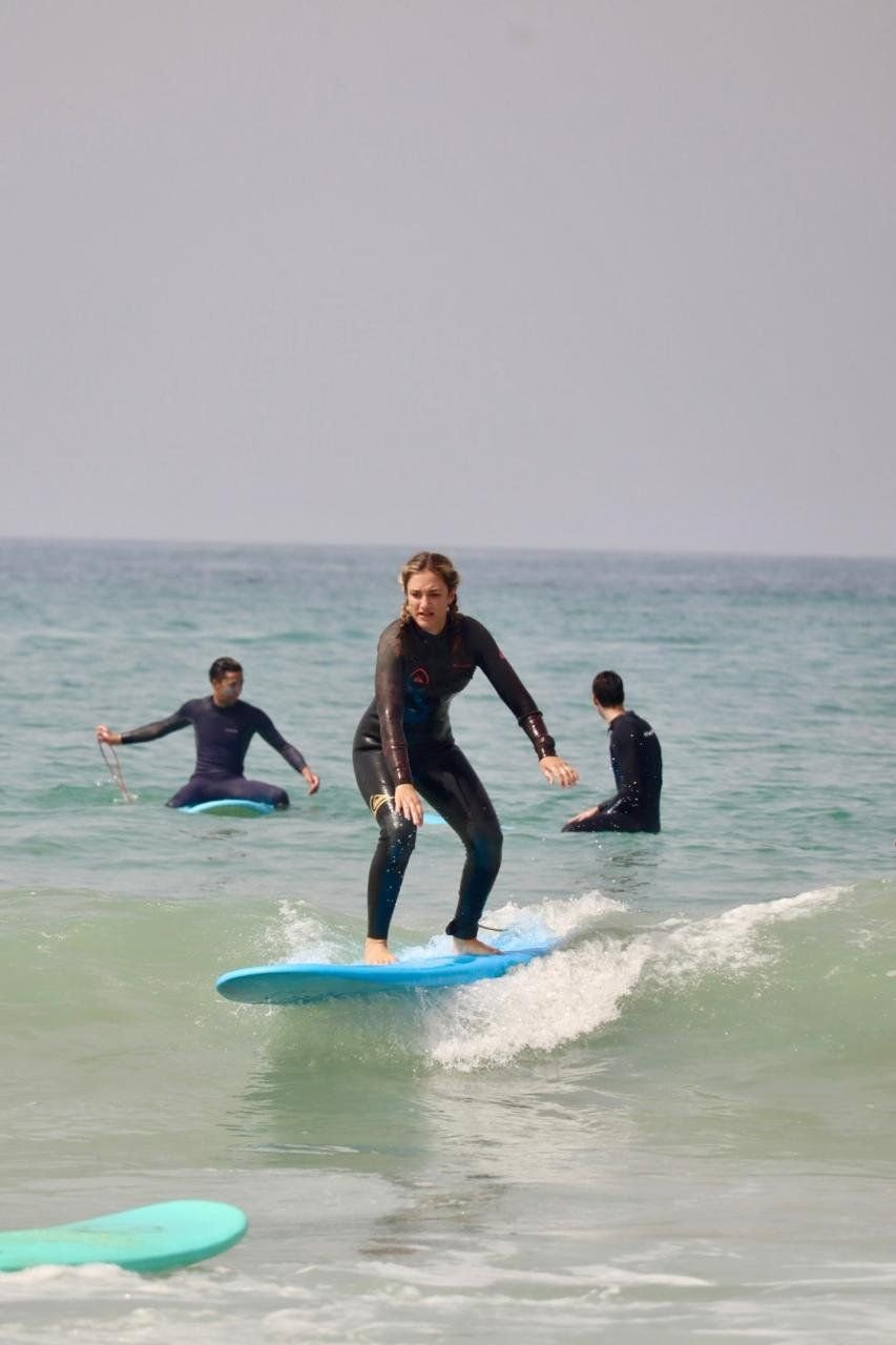 Intermediate surfer riding a wave in front of the coach
