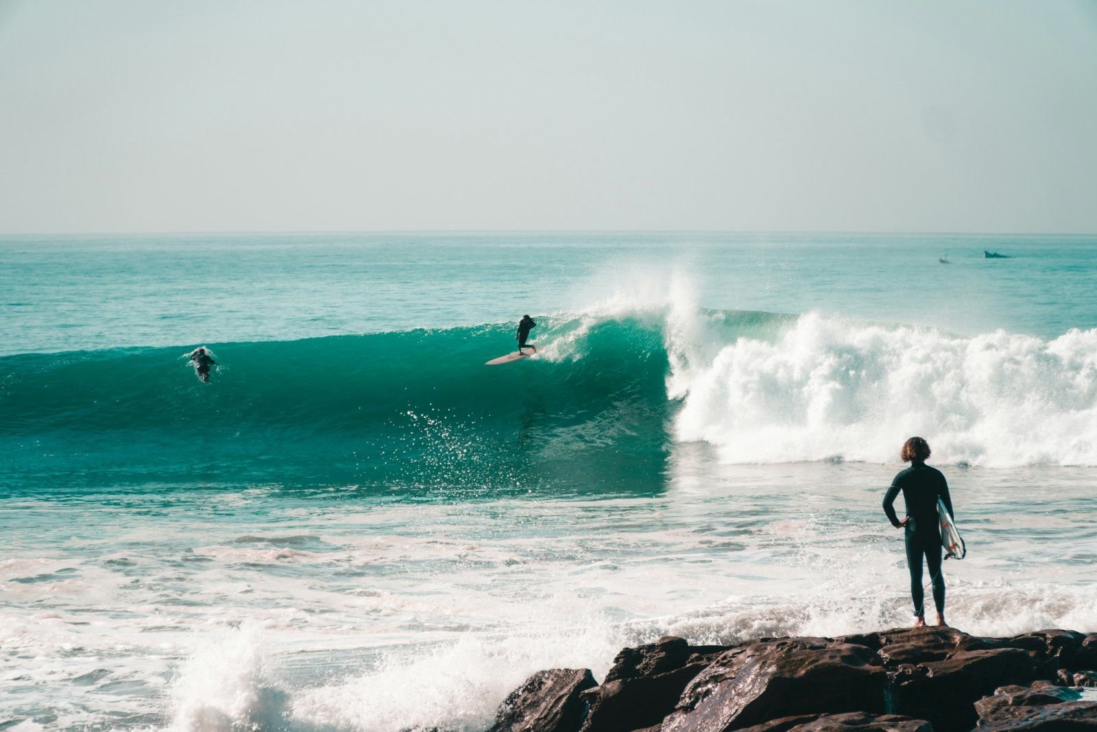 Surfer watching a long right-hand wave break in Taghazout