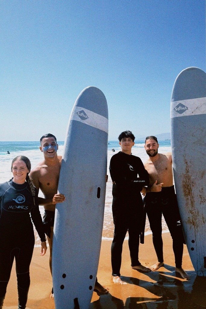 Four surfers holding their boards on the beach