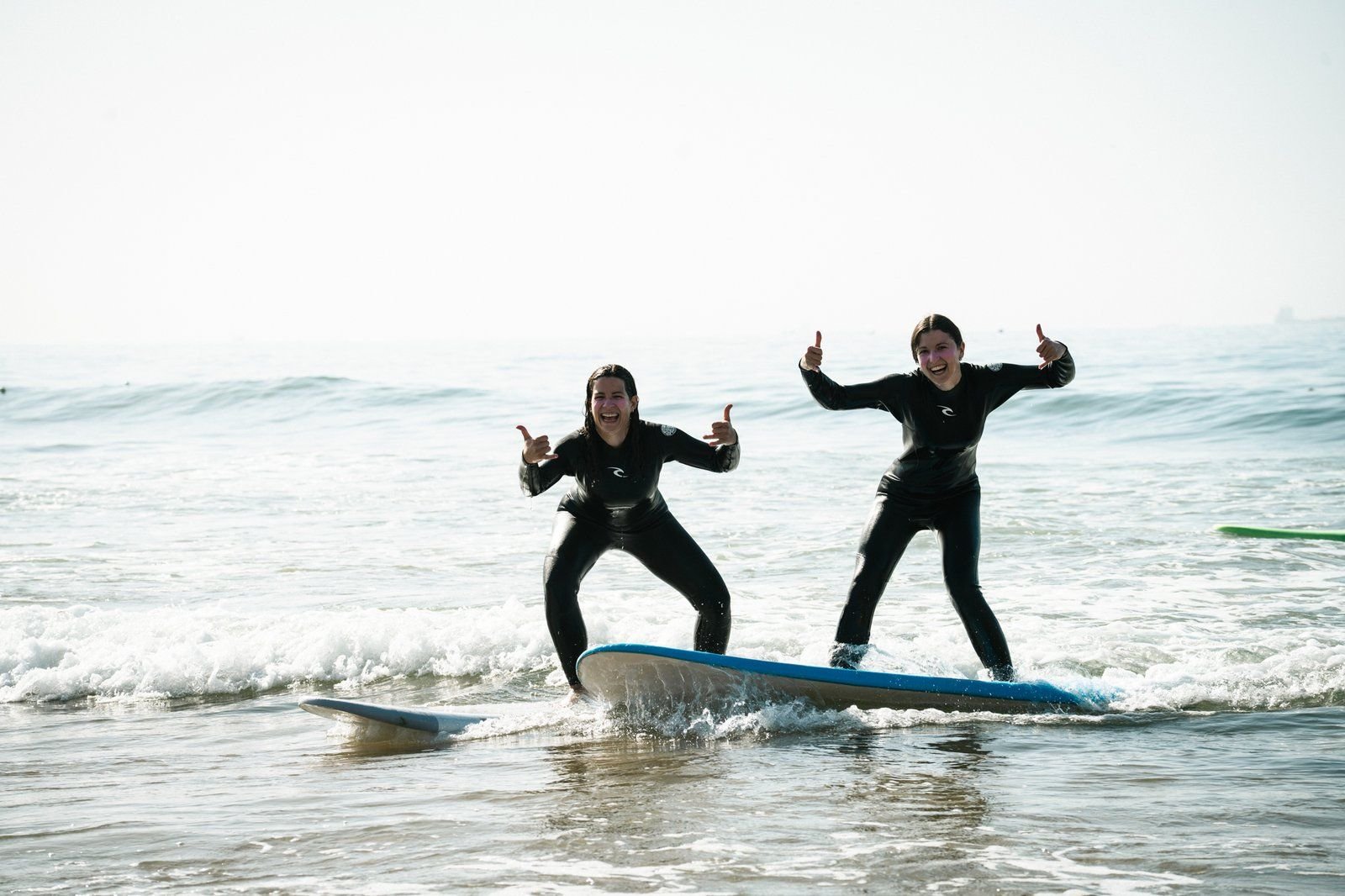 Two students riding one surfboard together at our surf camp in Taghazout